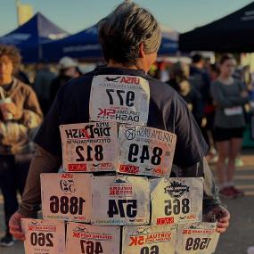 Older hispanic woman faced away from the camera with many years of DipDash bibs on her back like feathers